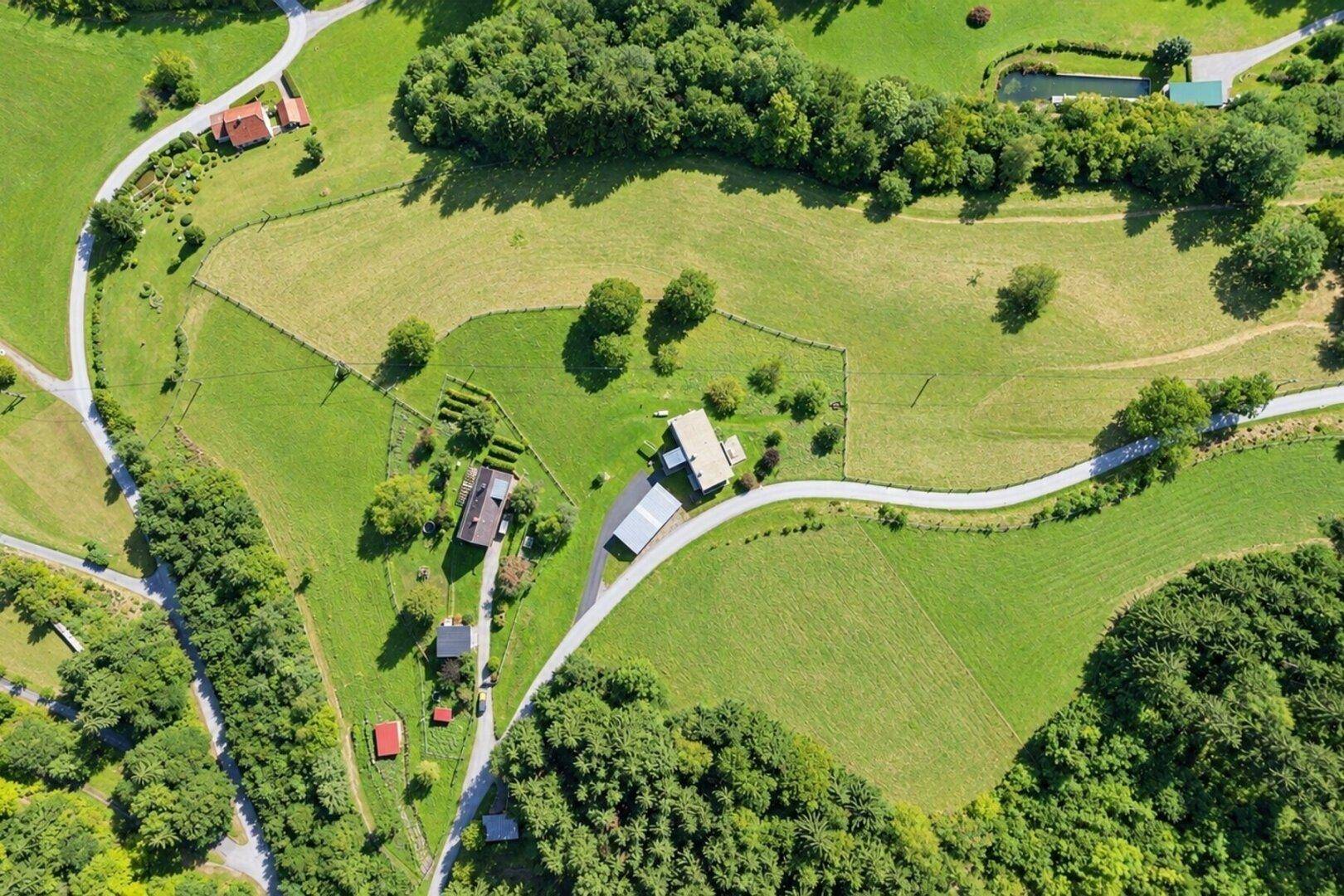 Vogelperspektive des Anwesens, eingebettet in eine weitläufige Landschaft aus Feldern und Wäldern.