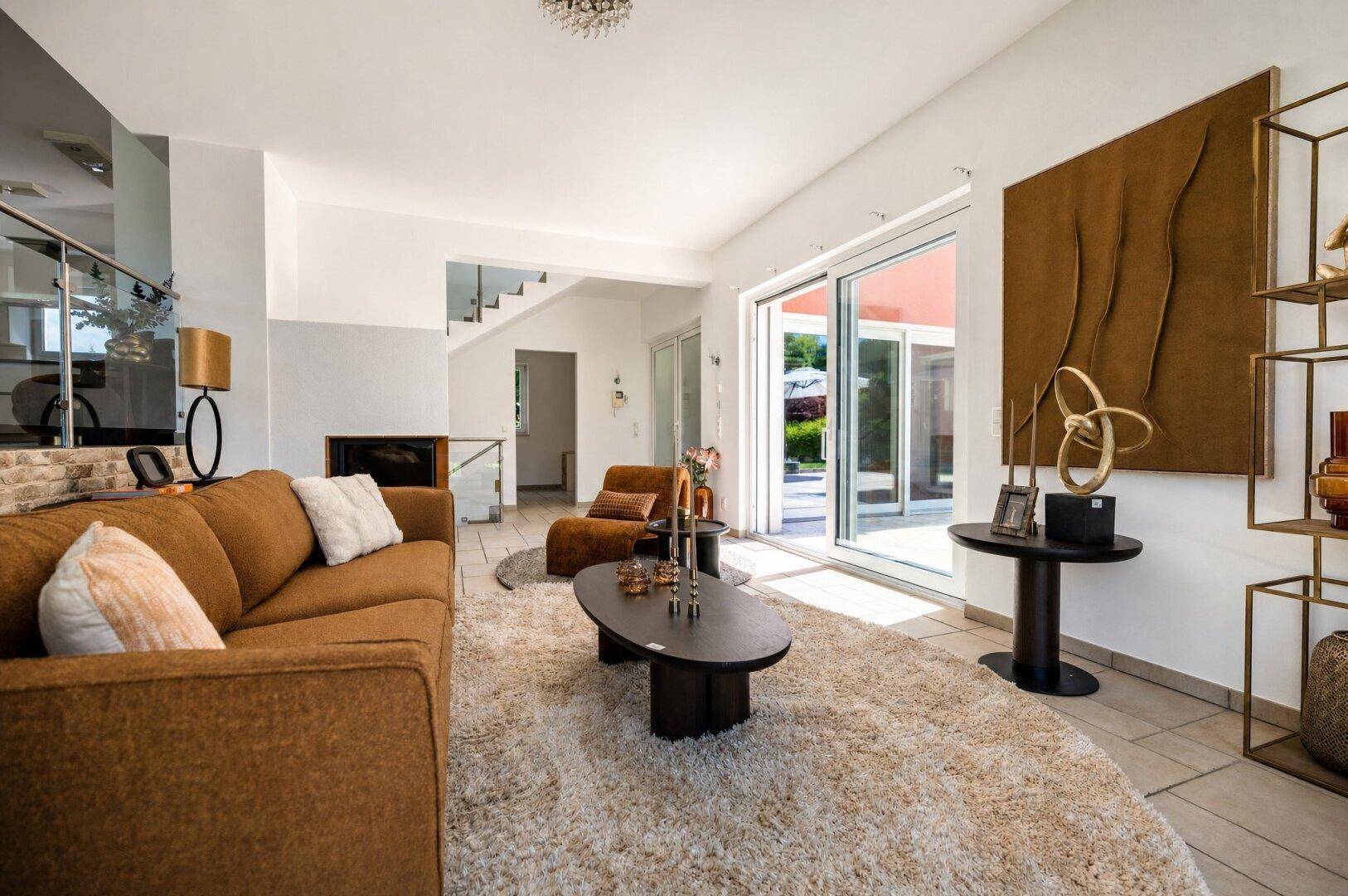 Geräumiges Wohnzimmer mit großen Schiebetüren, moderner Kunst und Zugang zum Außenbereich.
