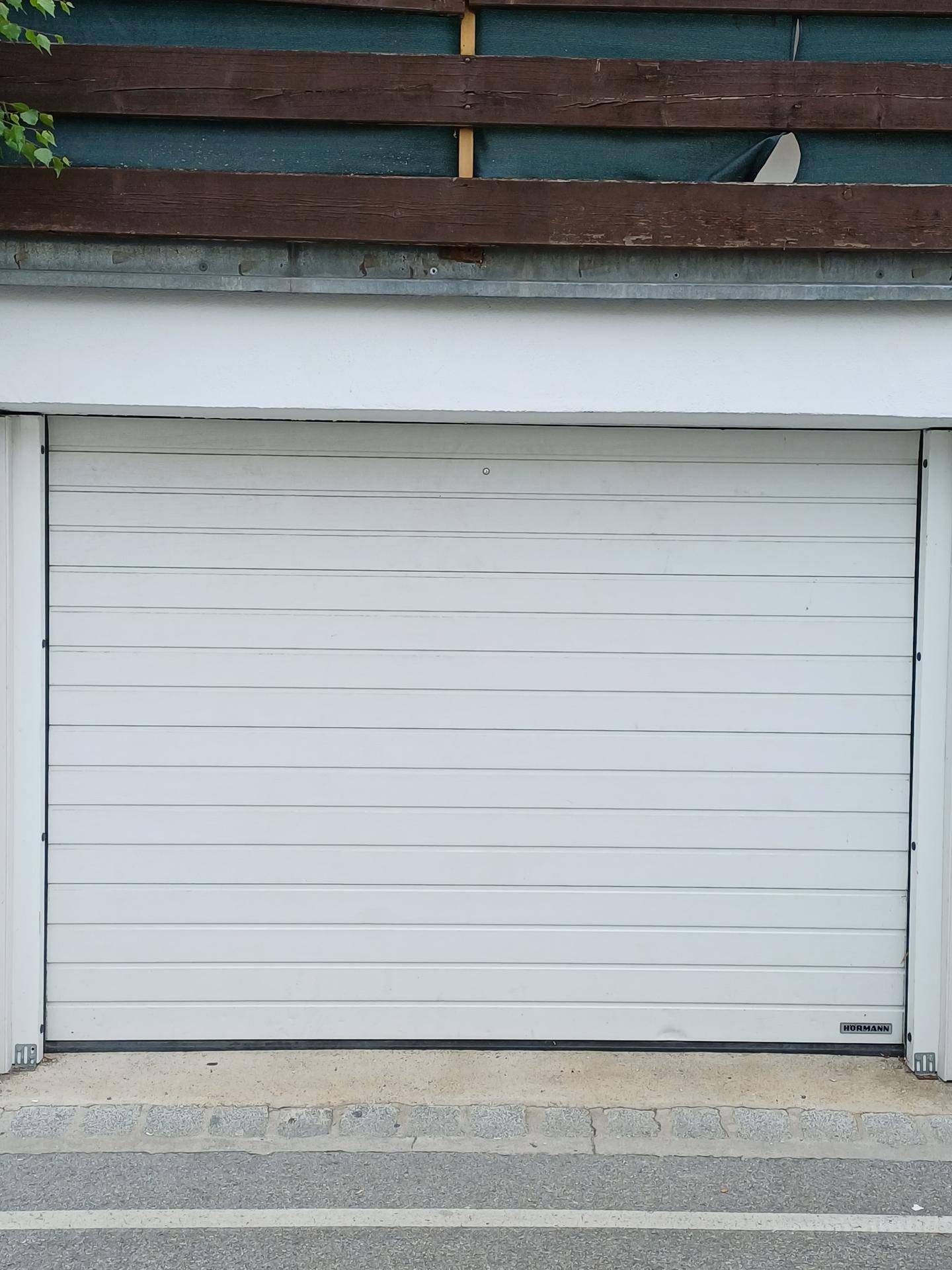 Weiße Garagentür mit horizontalen Lamellen, bietet sicheren Parkplatz für Fahrzeuge.