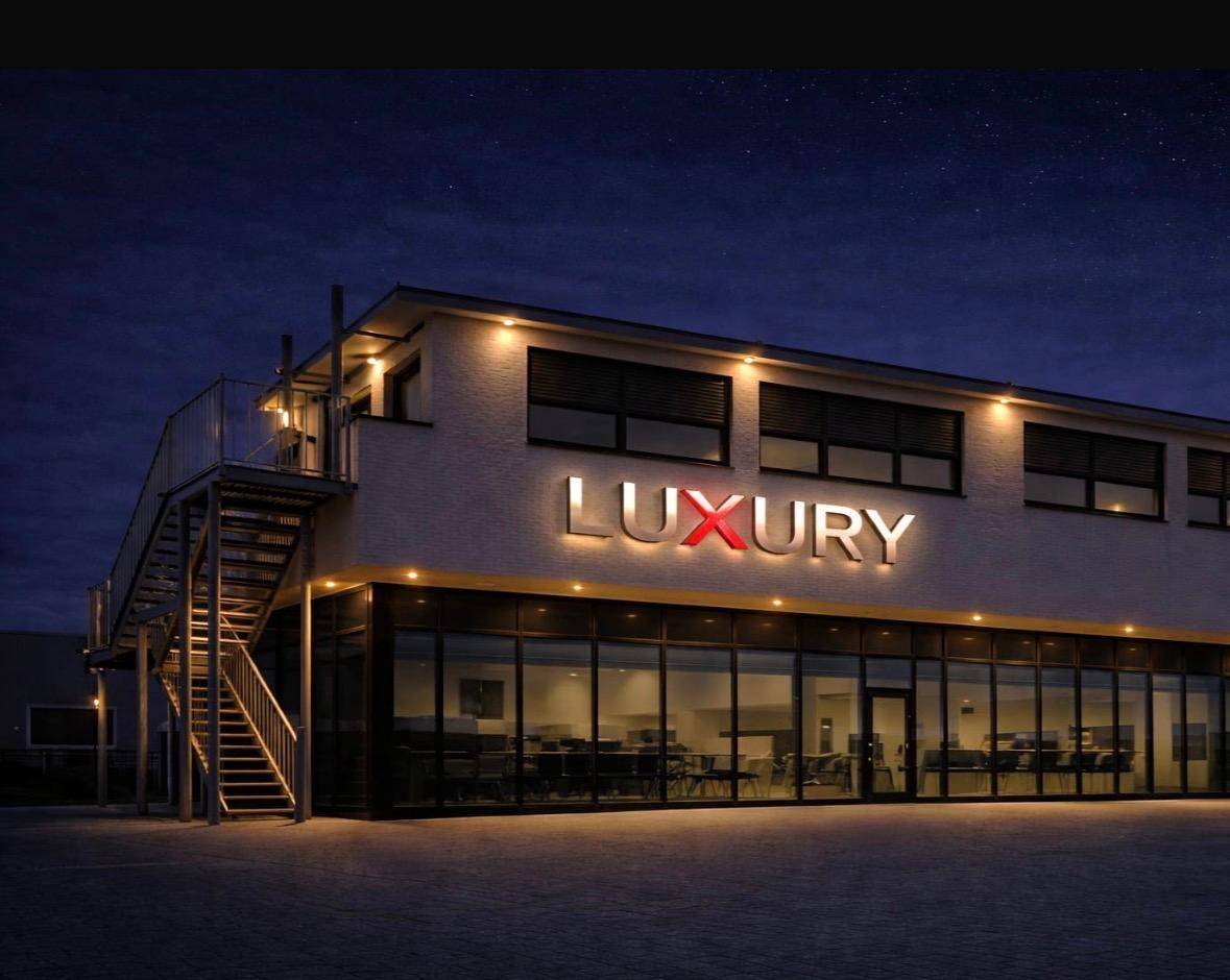 Beleuchtetes Geschäftsgebäude bei Nacht mit großer Glasfront und auffälliger "Luxury"-Beschriftung.