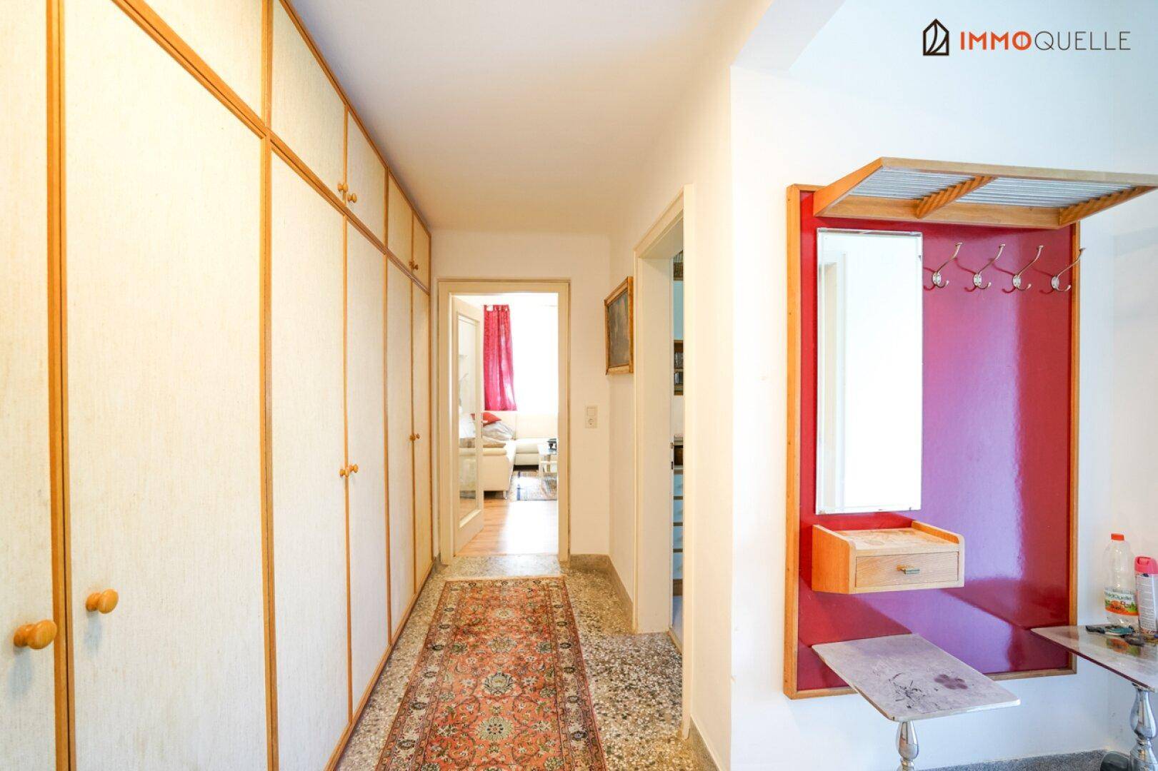 Flur mit Einbauschränken, Garderobe und Teppichläufer, der den Zugang zu anderen Räumen ermöglicht.