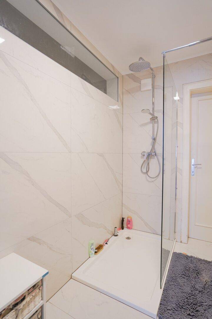 Geräumige, ebenerdige Dusche mit Glasabtrennung und modernen Fliesen im Badezimmer.