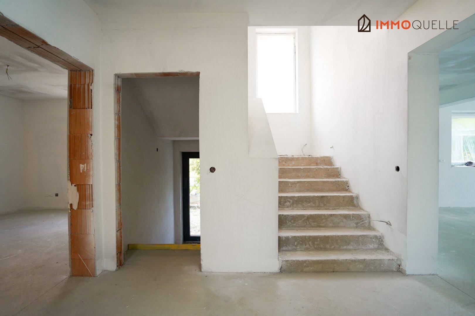 Unfertiger Innenraum mit Treppe und Rohbauwänden, bereit für den Ausbau.