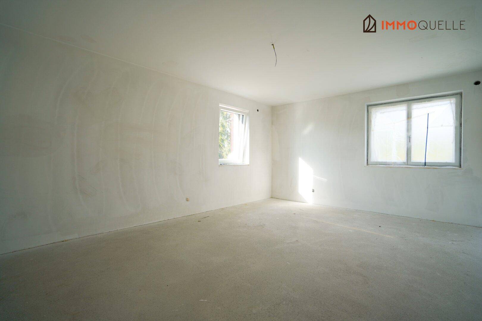 Heller Rohbauraum mit zwei Fenstern, bereit für den weiteren Innenausbau.