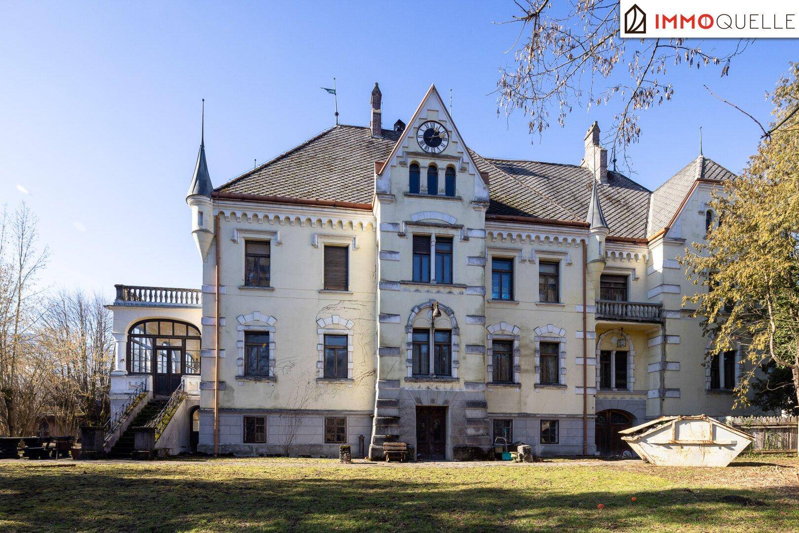 Vorderansicht der historischen Villa mit Uhr, architektonischen Details und weitläufigem Grundstück.