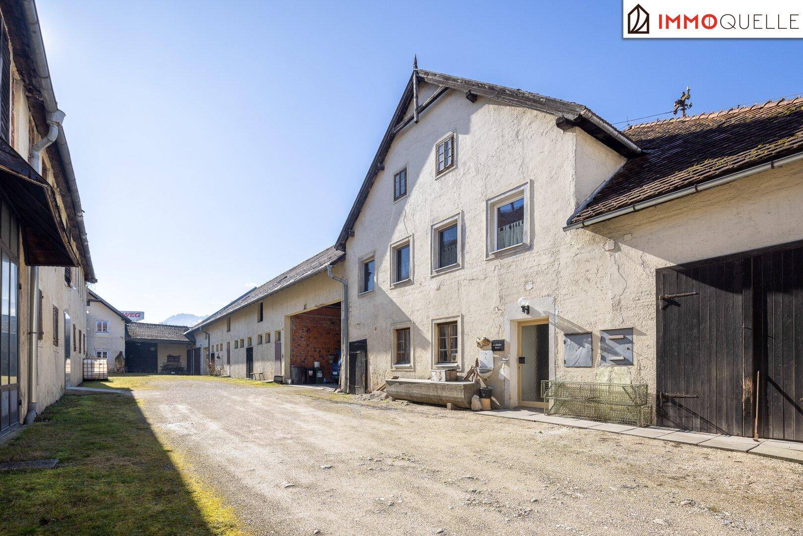 Ländliches Anwesen mit großem Hof und weiteren Wirtschaftsgebäuden unter blauem Himmel.