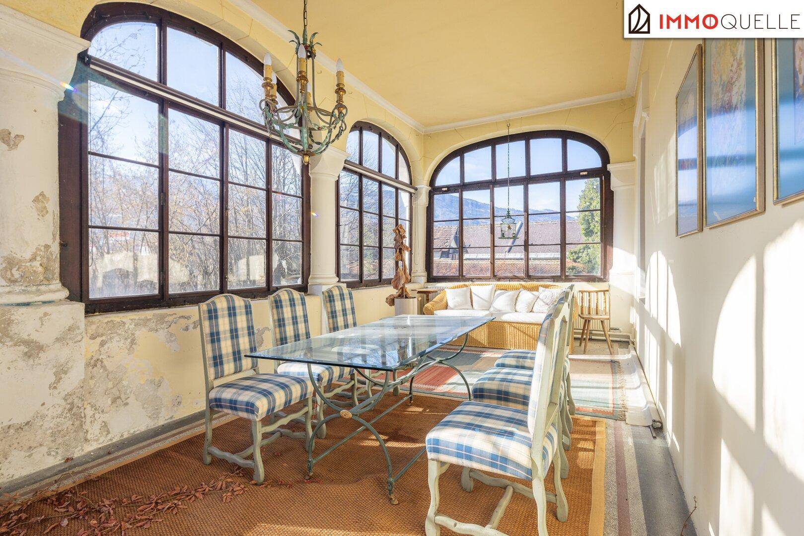 Heller Essbereich in einer verglasten Veranda mit Blick auf die Landschaft und die Berge.
