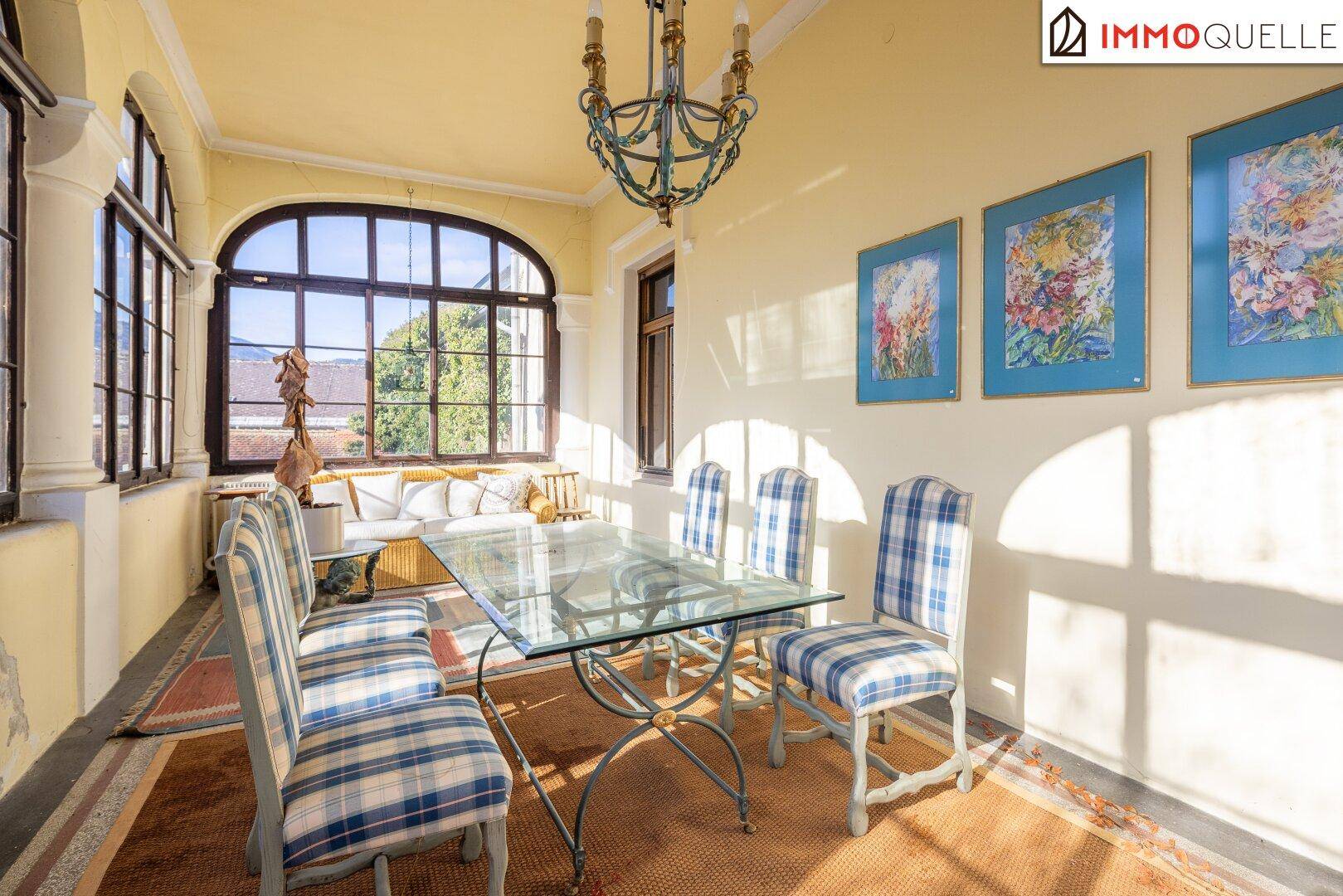 Sonniger Essbereich mit karierten Stühlen und großzügigen Fenstern in der Veranda.