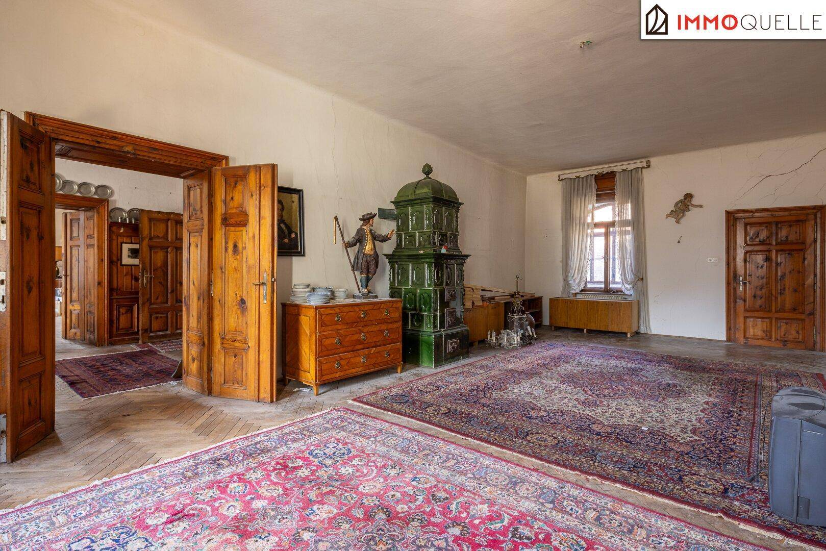 Großes Wohnzimmer mit Holztüren, Kachelofen und antiken Möbeln, die den Charme unterstreichen.