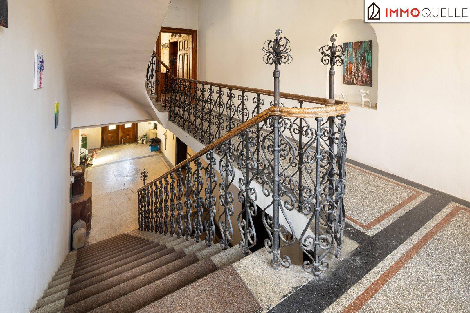Elegantes Treppenhaus mit schmiedeeisernem Geländer und Terrazzoboden in der historischen Villa.