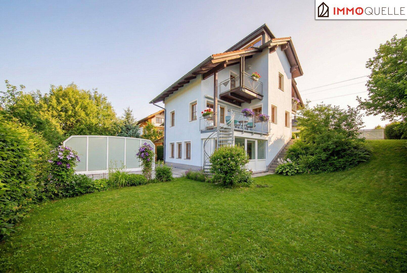 Seitenansicht des Hauses mit gepflegtem Rasen und üppiger Bepflanzung.