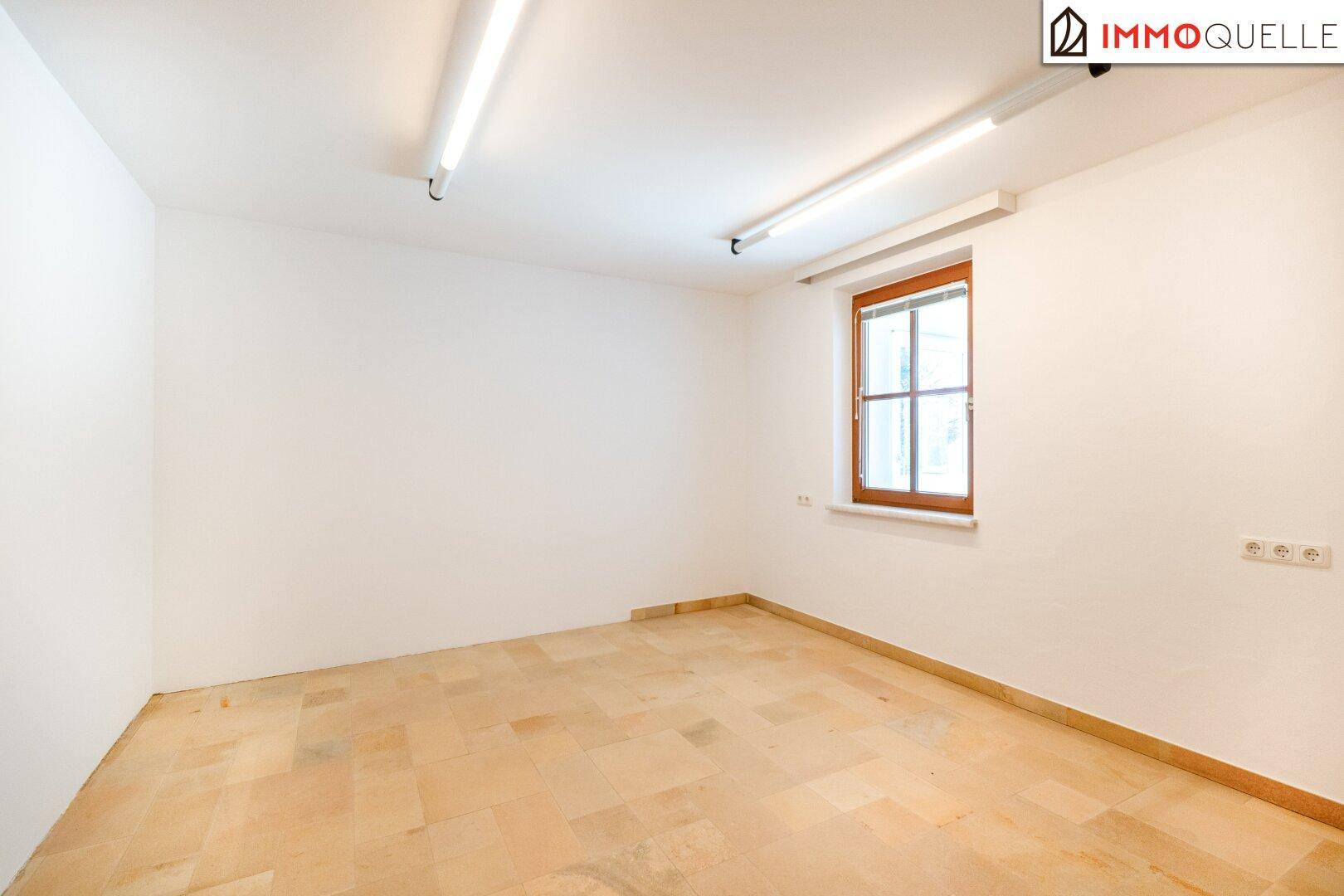Einfacher Raum mit Fliesenboden und einem Fenster, ideal als Abstellraum.