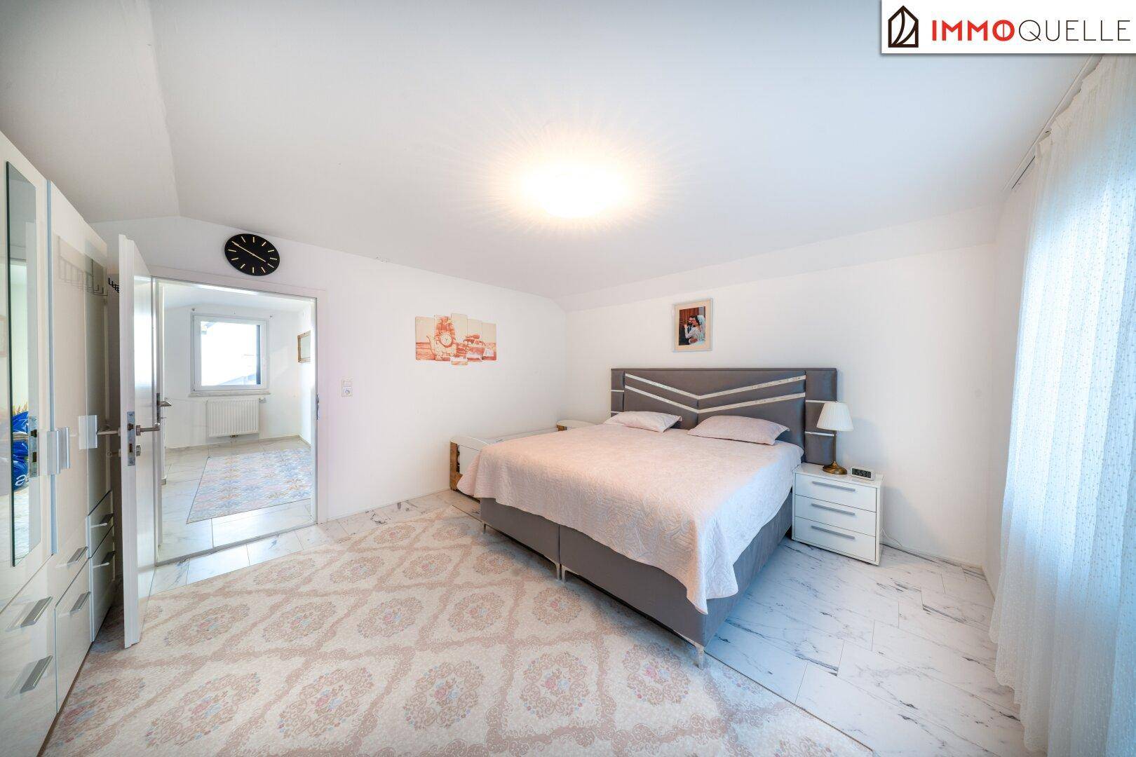 Geräumiges Schlafzimmer mit Doppelbett, weißem Kleiderschrank und hellen Marmorfliesen.