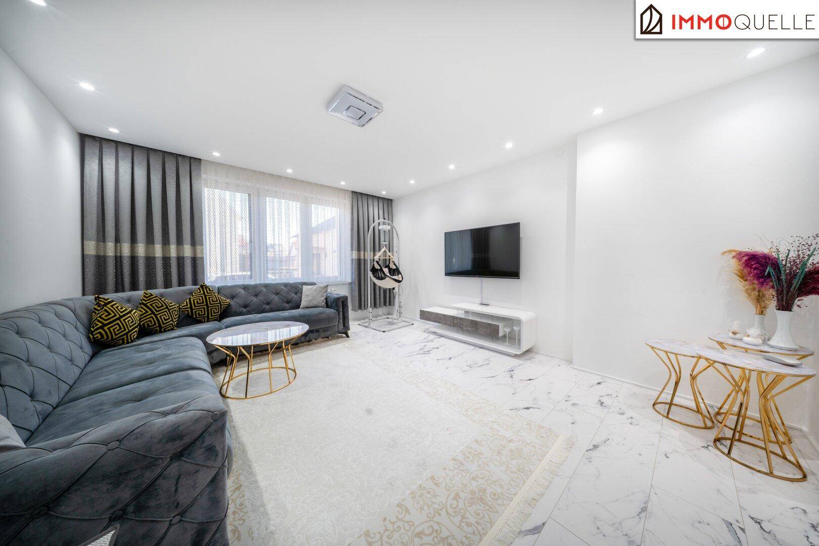 Modernes Wohnzimmer mit großem Ecksofa, Flachbildfernseher und eleganten Marmorfliesen.