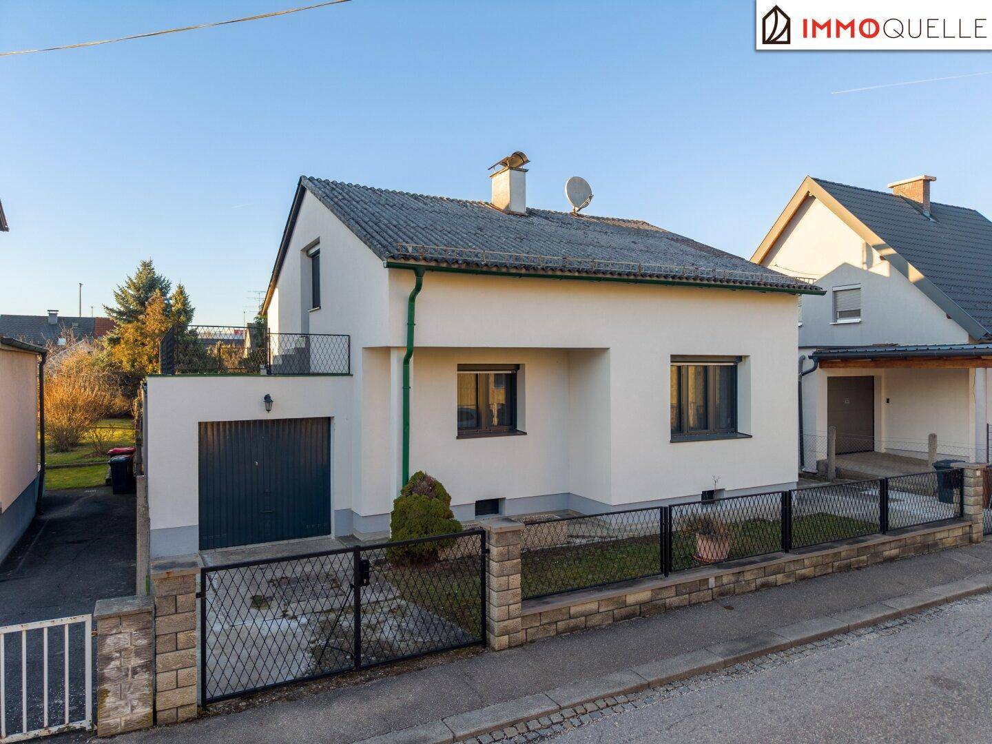 Vorderansicht des Einfamilienhauses mit Garage und einem kleinen Vorgartenbereich.