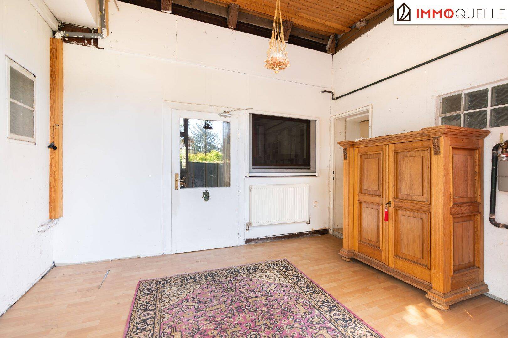 Heller Flur mit Holzboden, einem antiken Schrank und Zugang zum Garten.