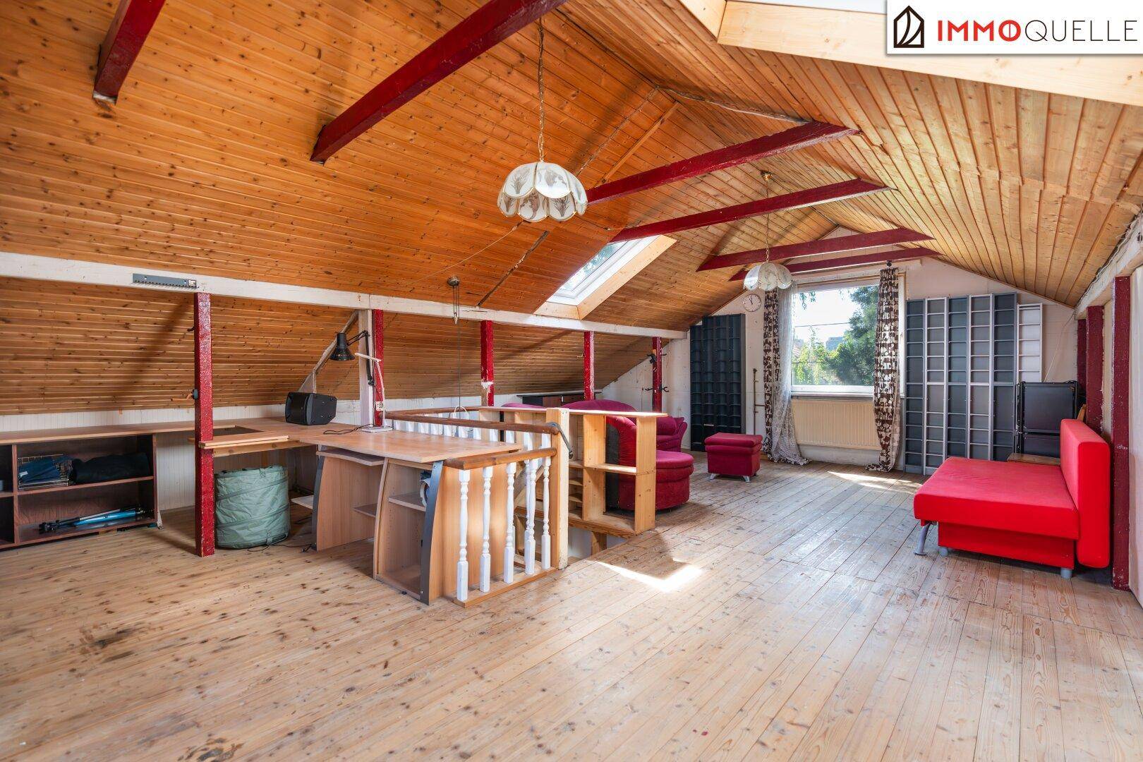 Ausgebauter Dachboden mit Holzvertäfelung, sichtbaren Balken und Dachfenstern.