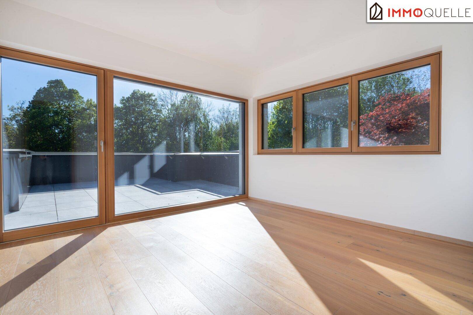 Geräumiges Schlafzimmer mit Holzboden und großen Fenstern mit Zugang zur Terrasse.
