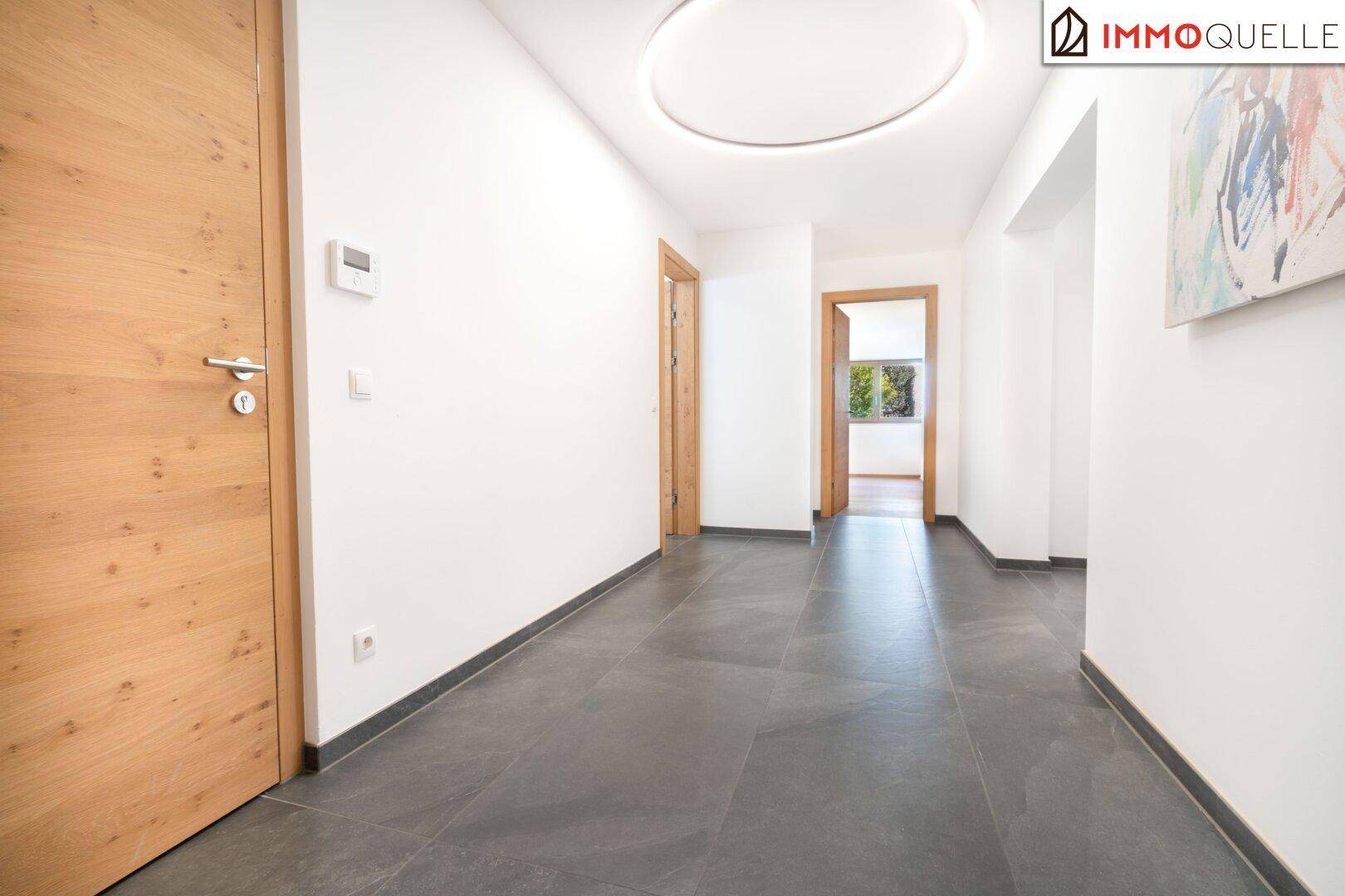Heller Flur mit Fliesenboden, Holztüren und moderner Deckenbeleuchtung.
