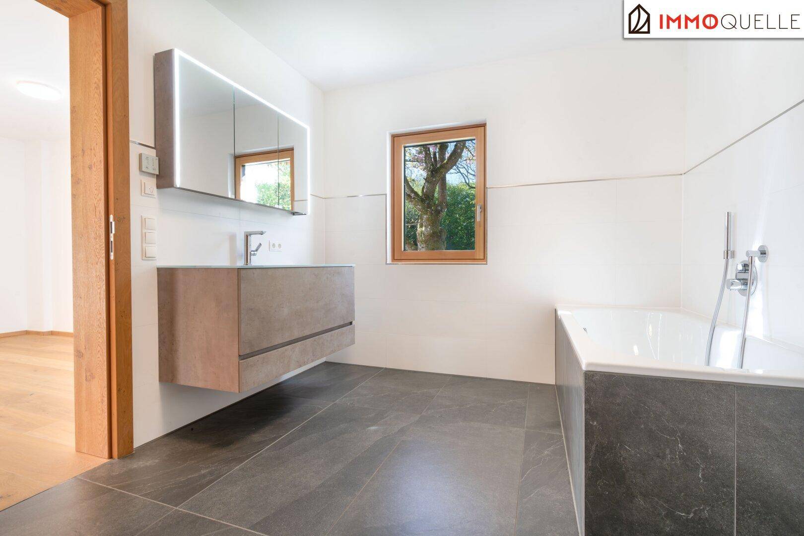 Modernes Badezimmer mit schwebendem Waschtisch, Badewanne und Fenster.