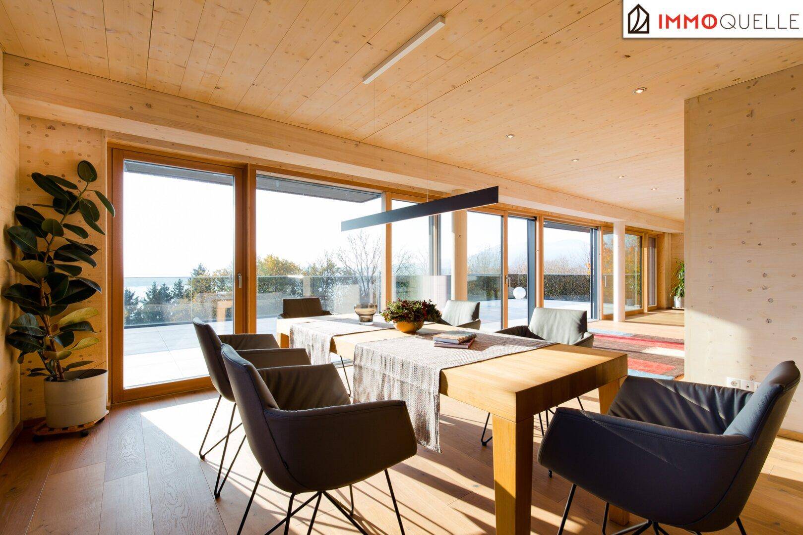 Lichtdurchfluteter Essbereich mit Holzwänden, Parkettboden und Zugang zur Terrasse mit Seeblick.