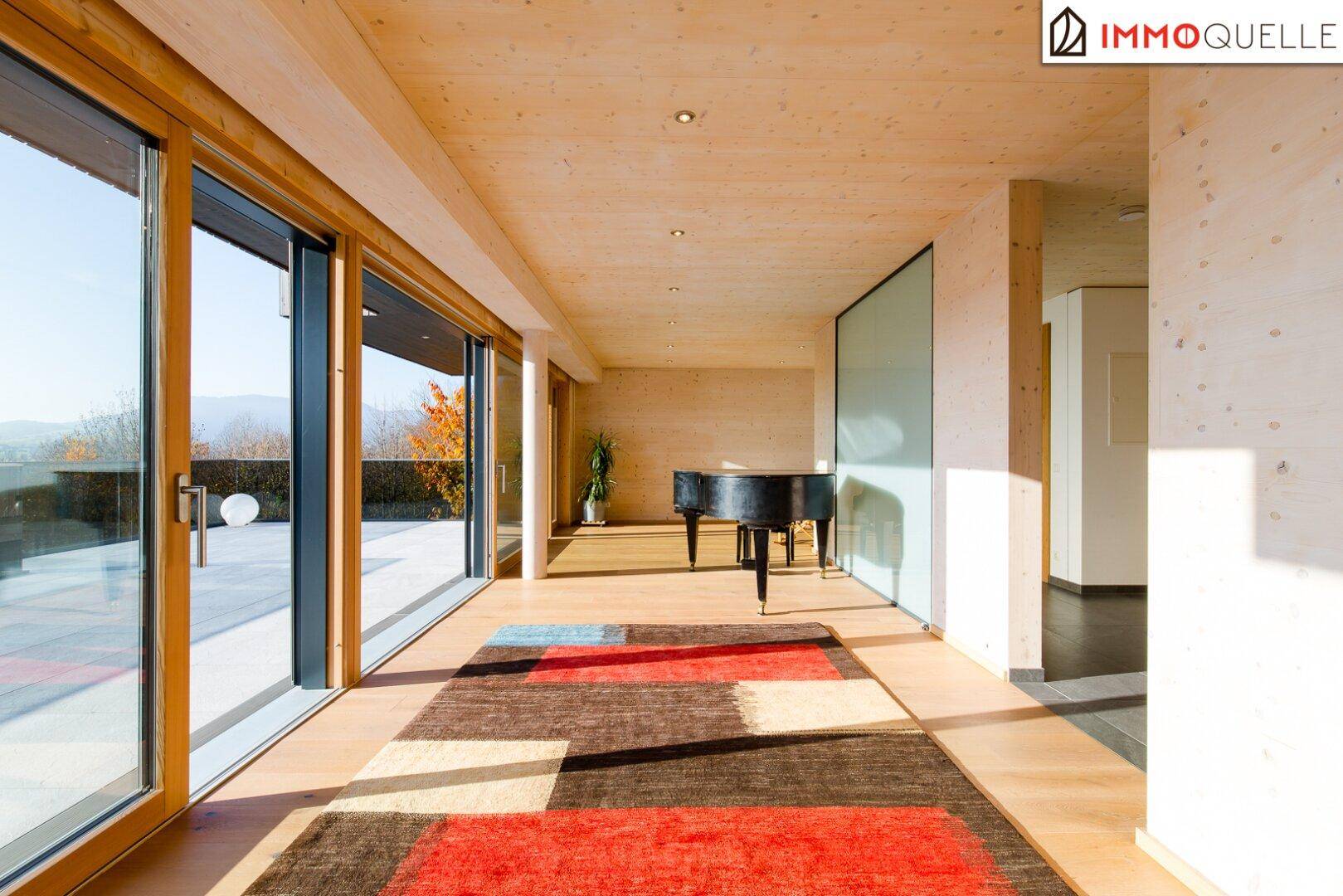 Heller Wohnbereich mit Holzboden, farbigem Teppich und Zugang zur Außenterrasse.