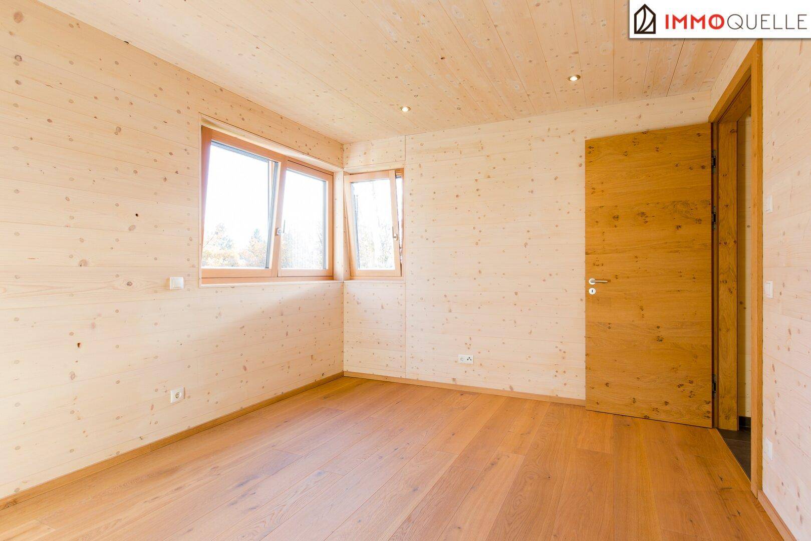 Geräumiges Schlafzimmer mit Holzboden und Fenstern, die viel Tageslicht hereinlassen.