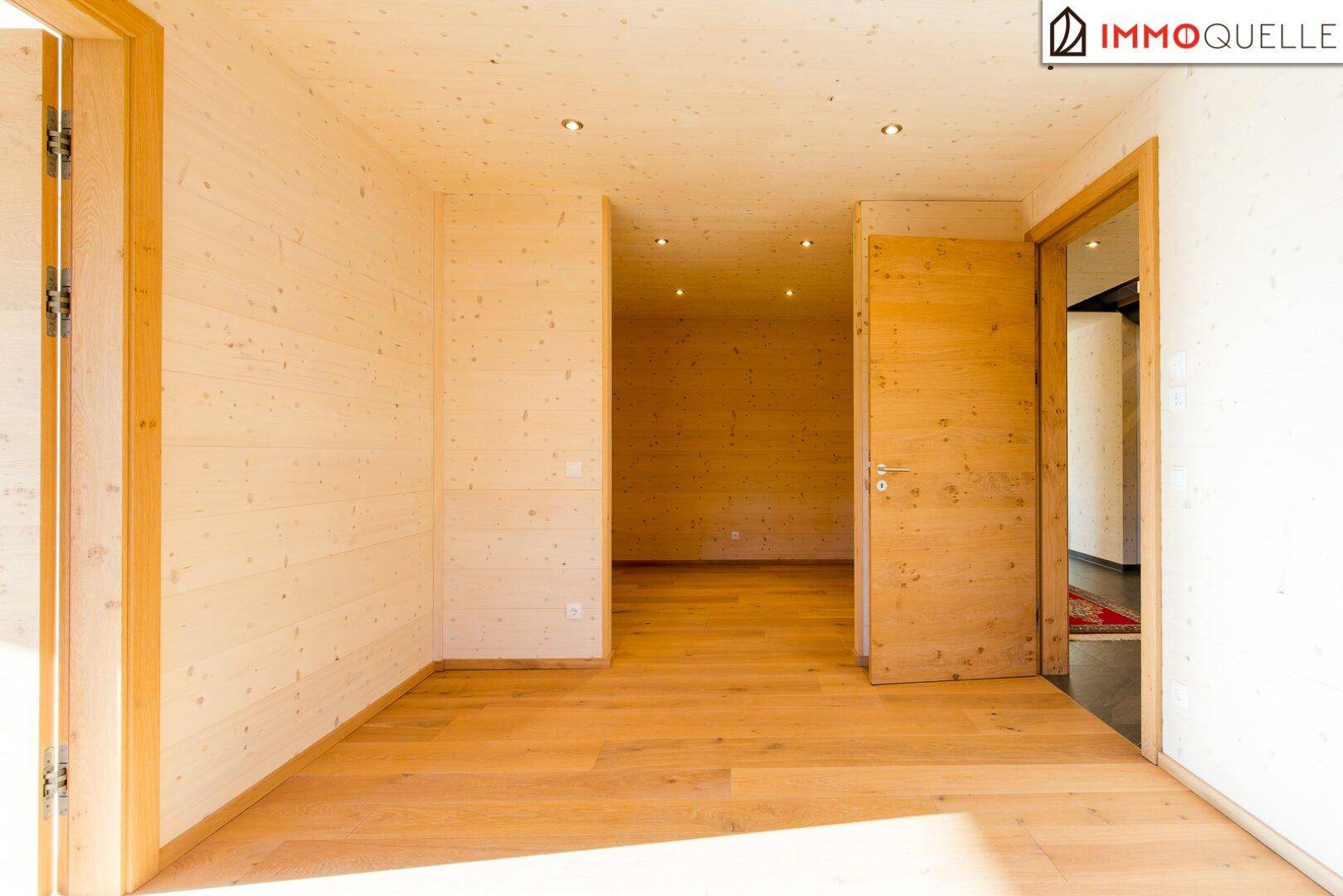 Heller Flur mit Holzboden und Holzwänden, der zu verschiedenen Räumen führt.