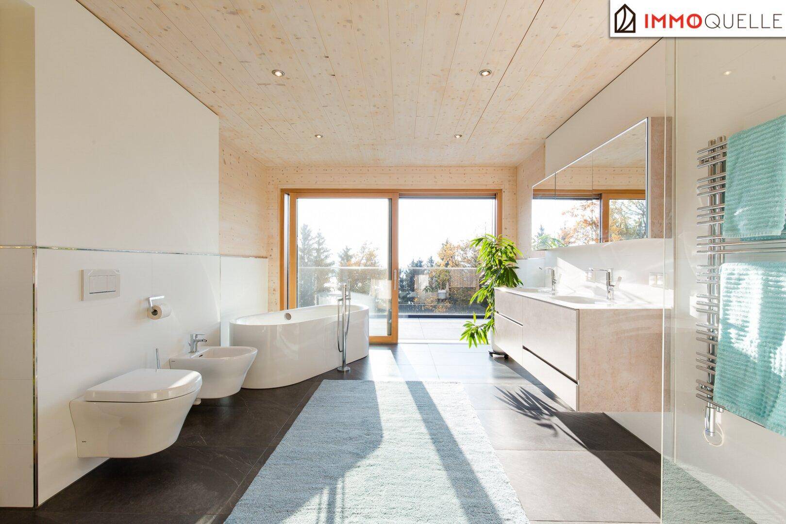 Modernes Badezimmer mit freistehender Badewanne, Doppelwaschbecken und Zugang zur Terrasse mit Aussicht.