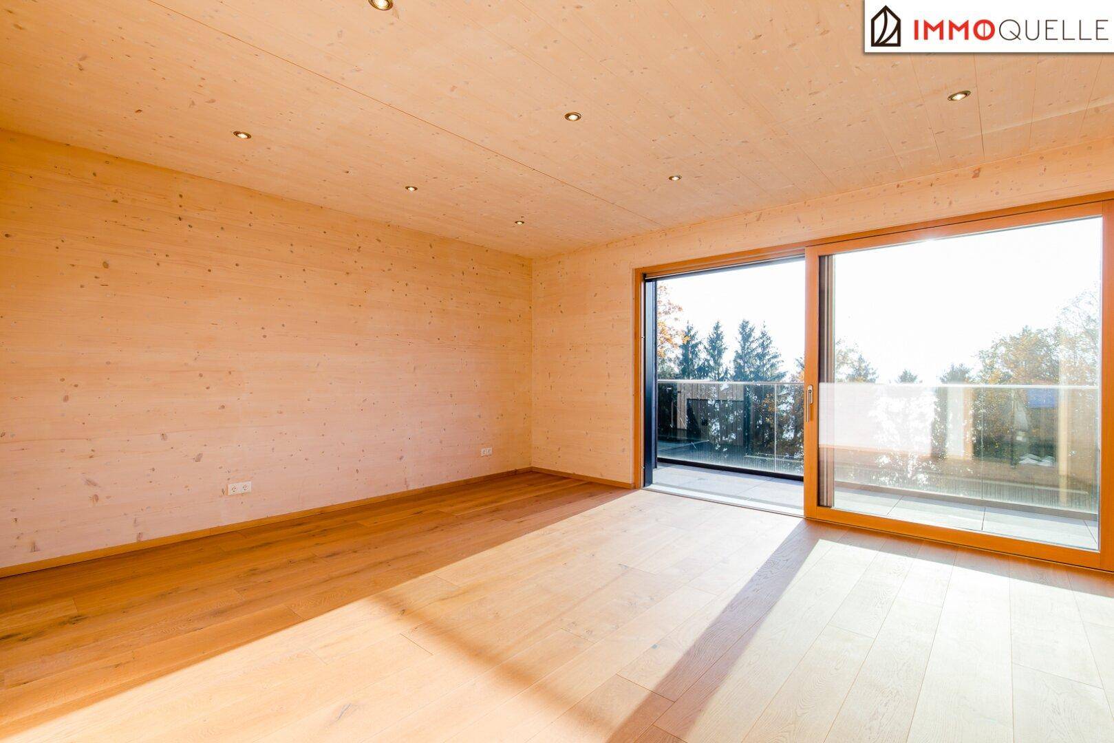 Geräumiges Schlafzimmer mit Holzboden und großen Schiebetüren, die viel Licht hereinlassen.