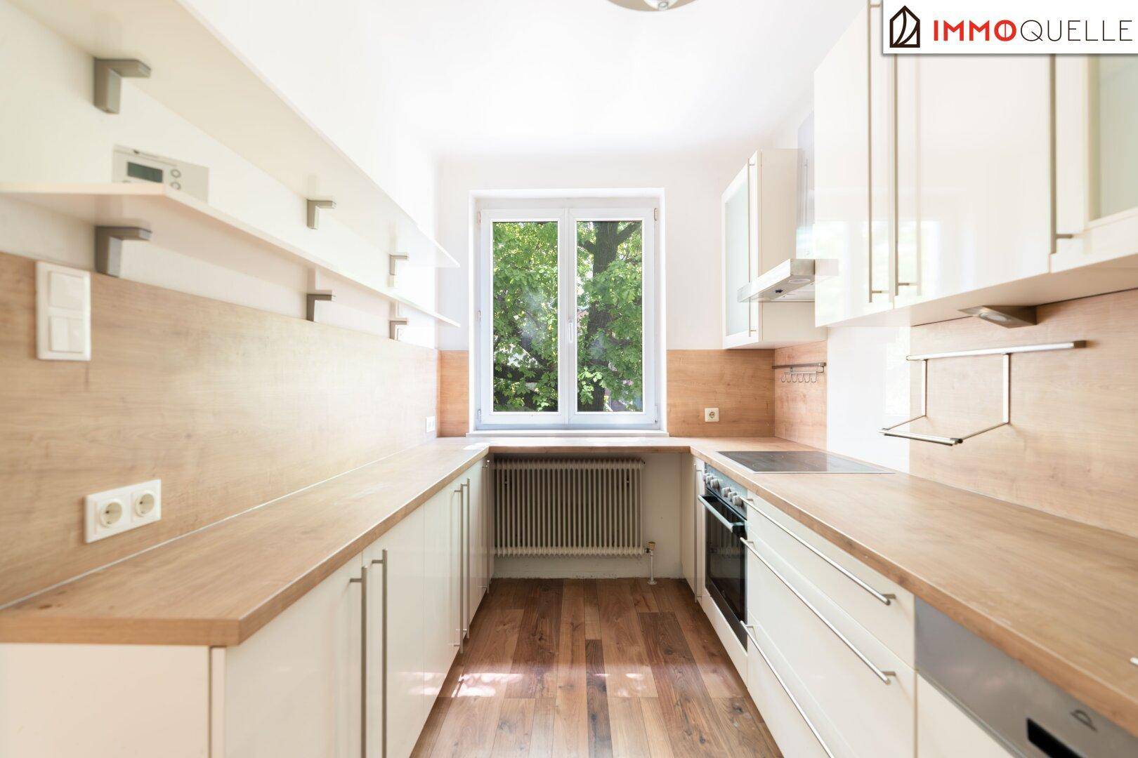 Funktionale Küche in U-Form mit hellen Fronten, Holz-Arbeitsplatten und Fenster für Tageslicht.