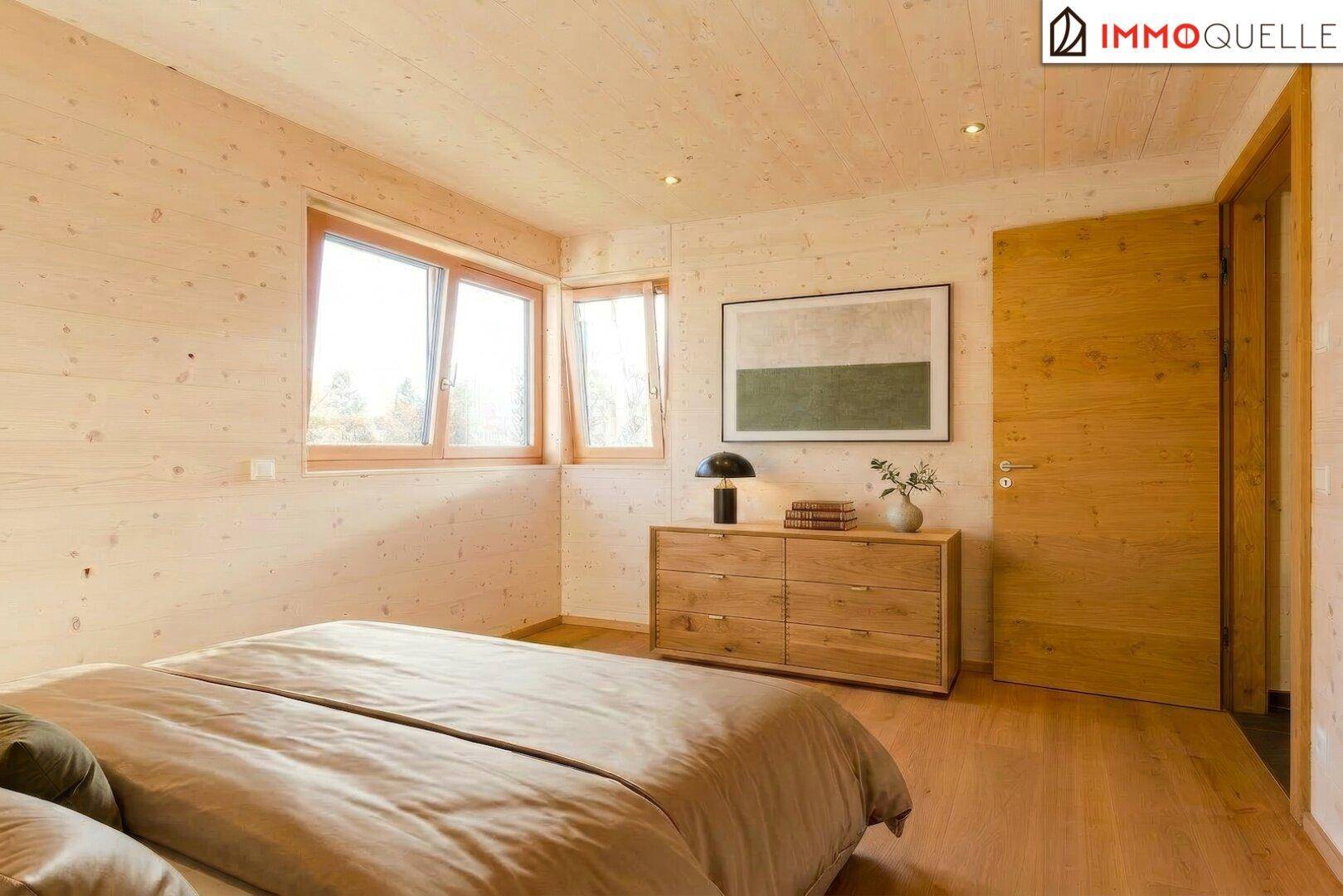 Gemütliches Schlafzimmer mit Holzwänden, Holzboden und einem Fenster mit Blick ins Grüne.