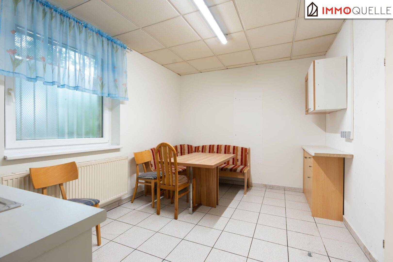 Gemütlicher Pausenraum für Mitarbeiter mit Esstisch, Sitzbank und einer kleinen Küchenzeile mit Oberschränken.
