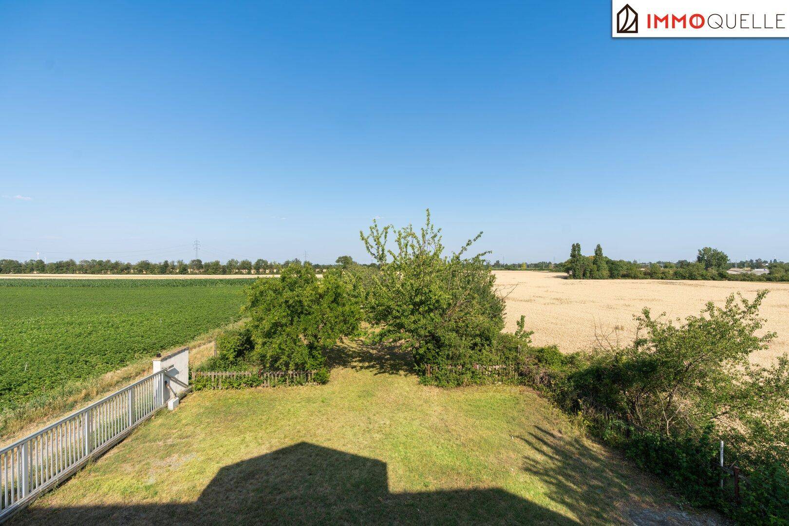 Panoramablick über weite Felder und grüne Landschaften von einem erhöhten Gartenbereich.