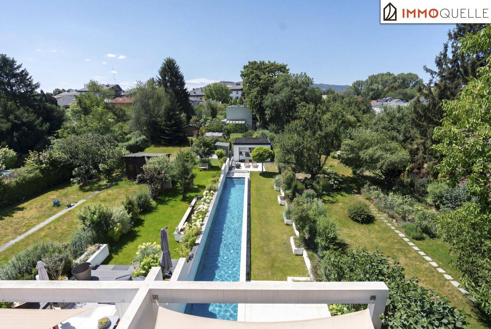 Weitläufige Außenansicht des Anwesens mit langem Pool, Garten und umliegender Landschaft.