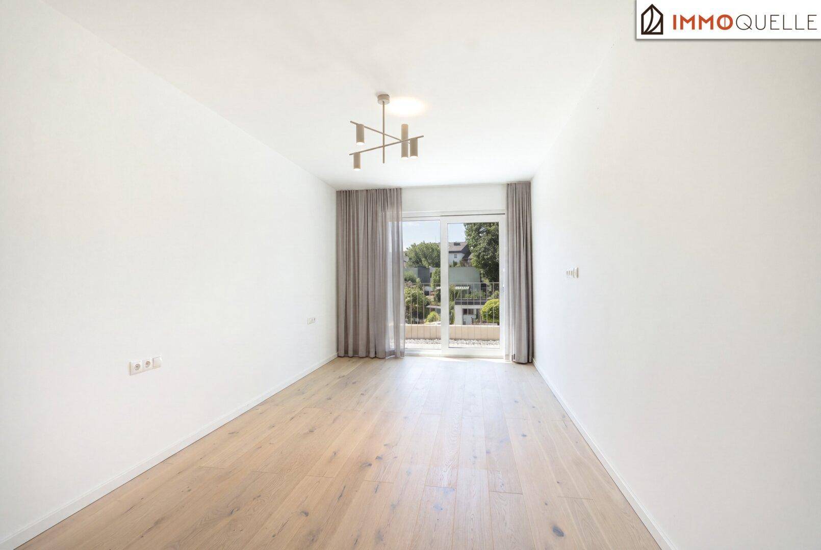 Heller, unmöblierter Raum mit Holzboden und Zugang zu einem französischen Balkon.
