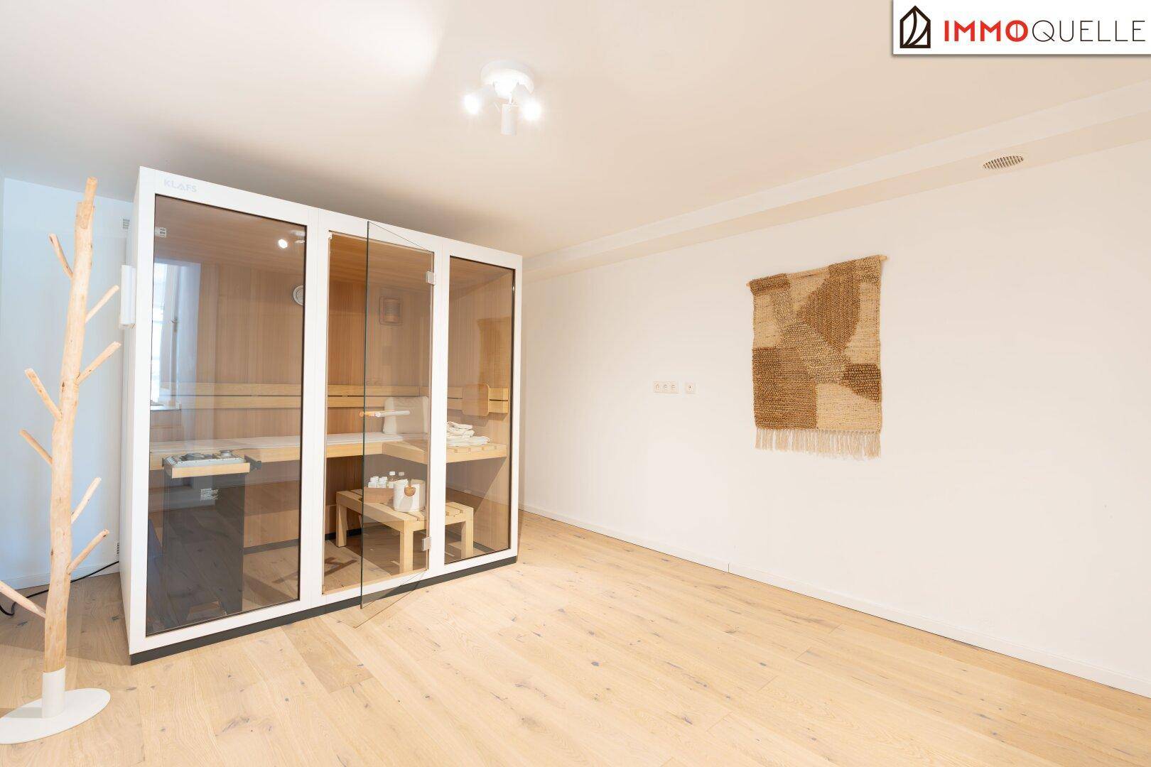 Geräumiger Raum mit moderner Sauna, Holzboden und schlichter Wanddekoration.
