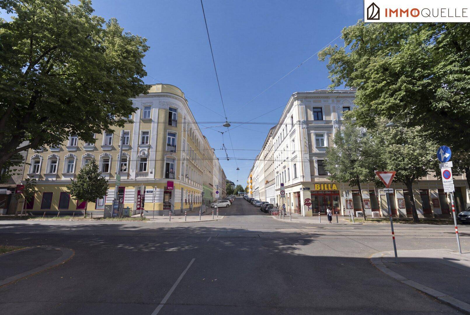 Eine städtische Kreuzung mit mehrstöckigen Gebäuden auf beiden Seiten, typisch für ein Stadtviertel.
