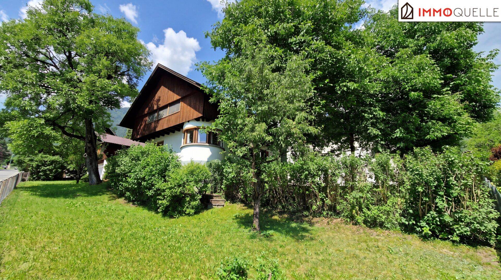Vorderansicht des Hauses mit großem Garten und üppiger Bepflanzung.