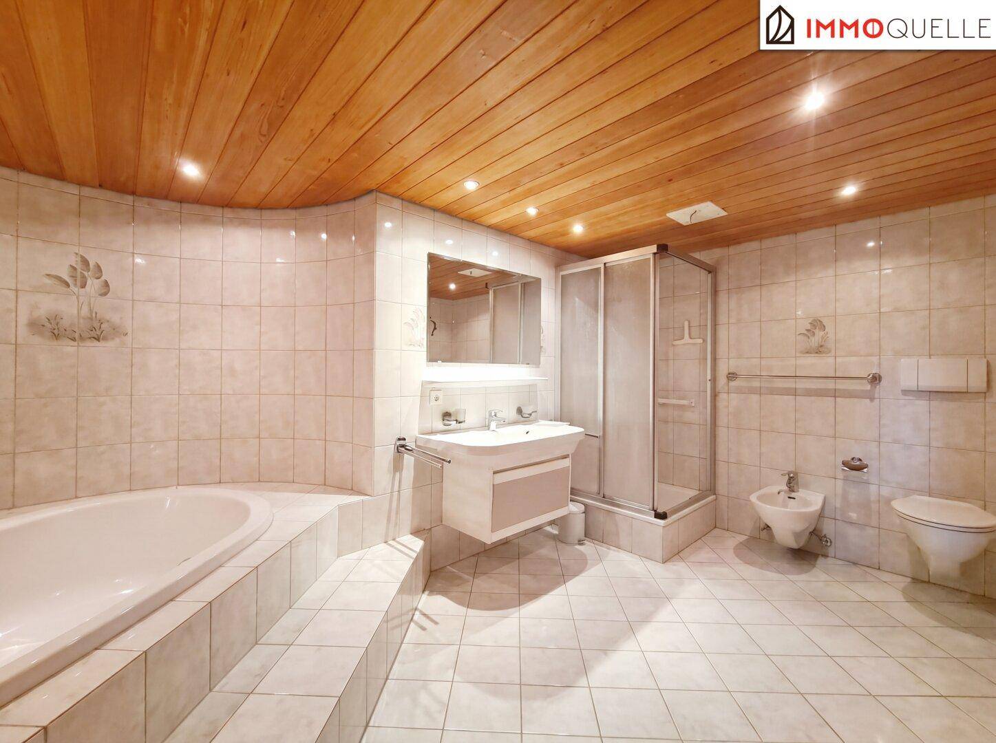 Geräumiges Badezimmer mit Fliesenboden, Badewanne, Dusche und Holzdecke.