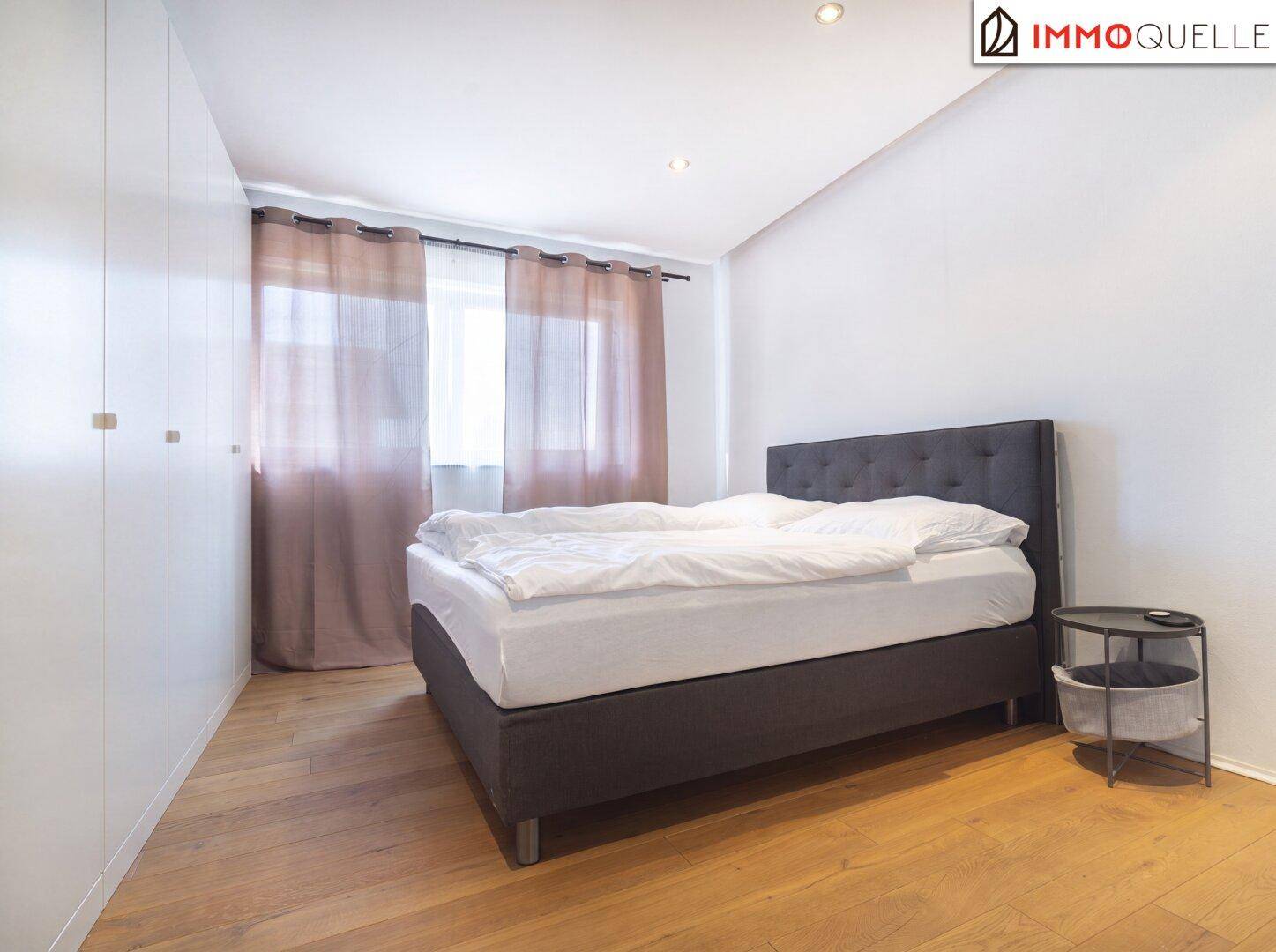 Helles Schlafzimmer mit Holzboden, großem Bett und integrierten weißen Kleiderschränken.