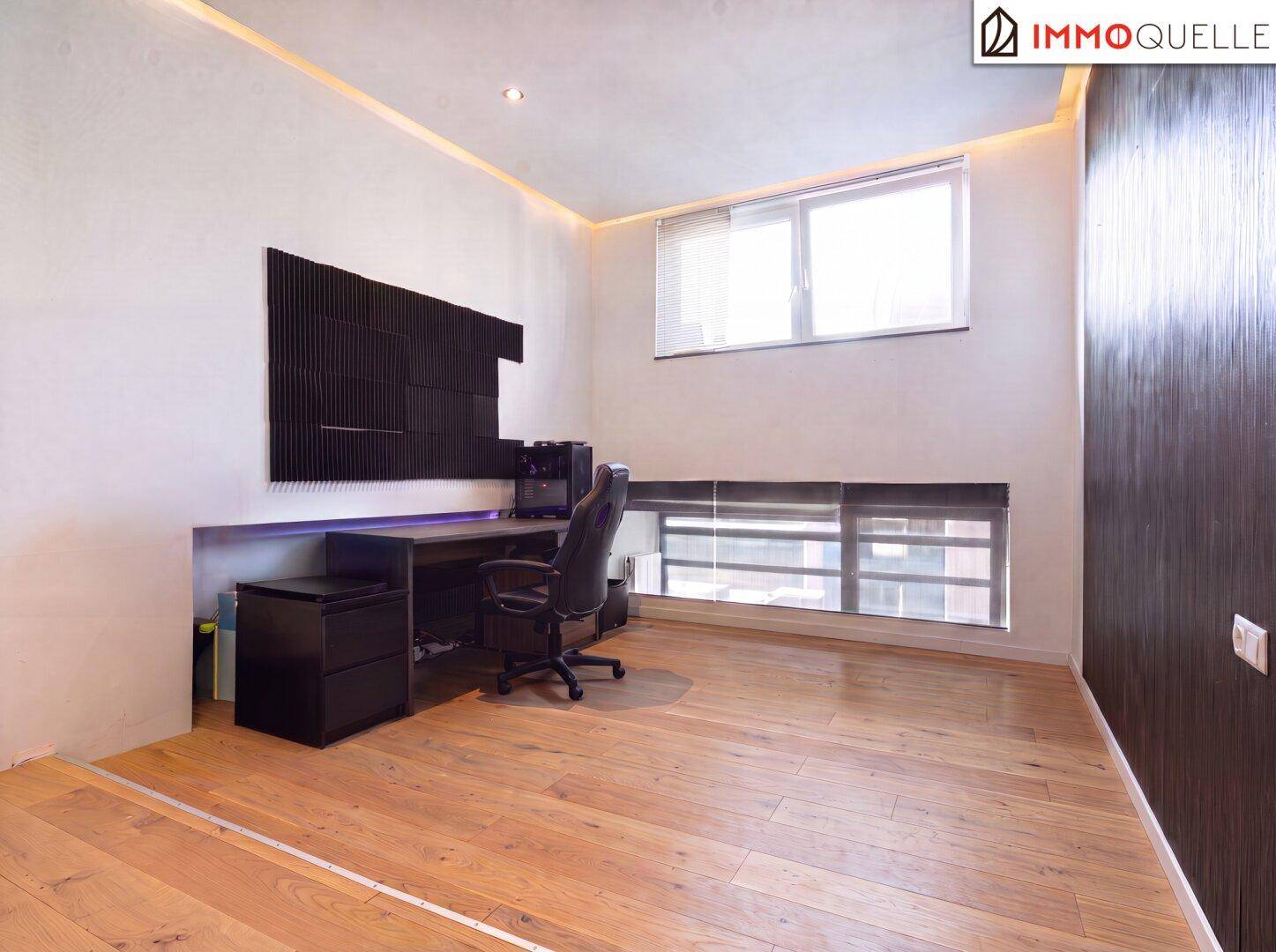 Modernes Arbeitszimmer mit Holzboden, großem Schreibtisch und Akustikpaneelen an der Wand.