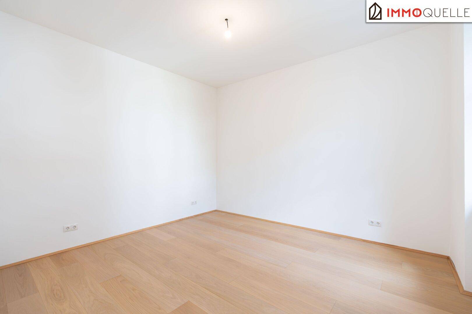 Schlichtes, leeres Zimmer mit hellem Holzboden und weißen Wänden, bereit zur individuellen Gestaltung.