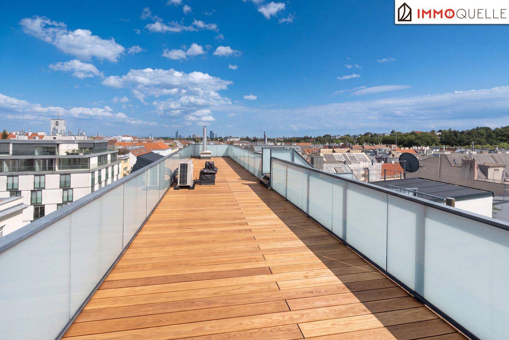 Weitläufige Dachterrasse mit Holzbelag und Panoramablick über die Stadt.