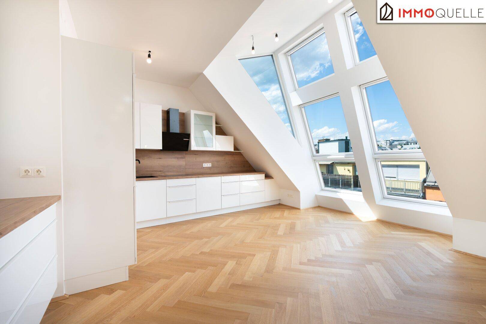 Helle, moderne Küche mit weißen Fronten, Holzboden und beeindruckenden Dachfenstern.