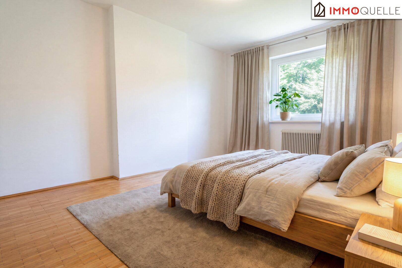 Ruhiges Schlafzimmer mit Holzbett, Teppich und Fenster mit Blick auf die umliegende Natur.