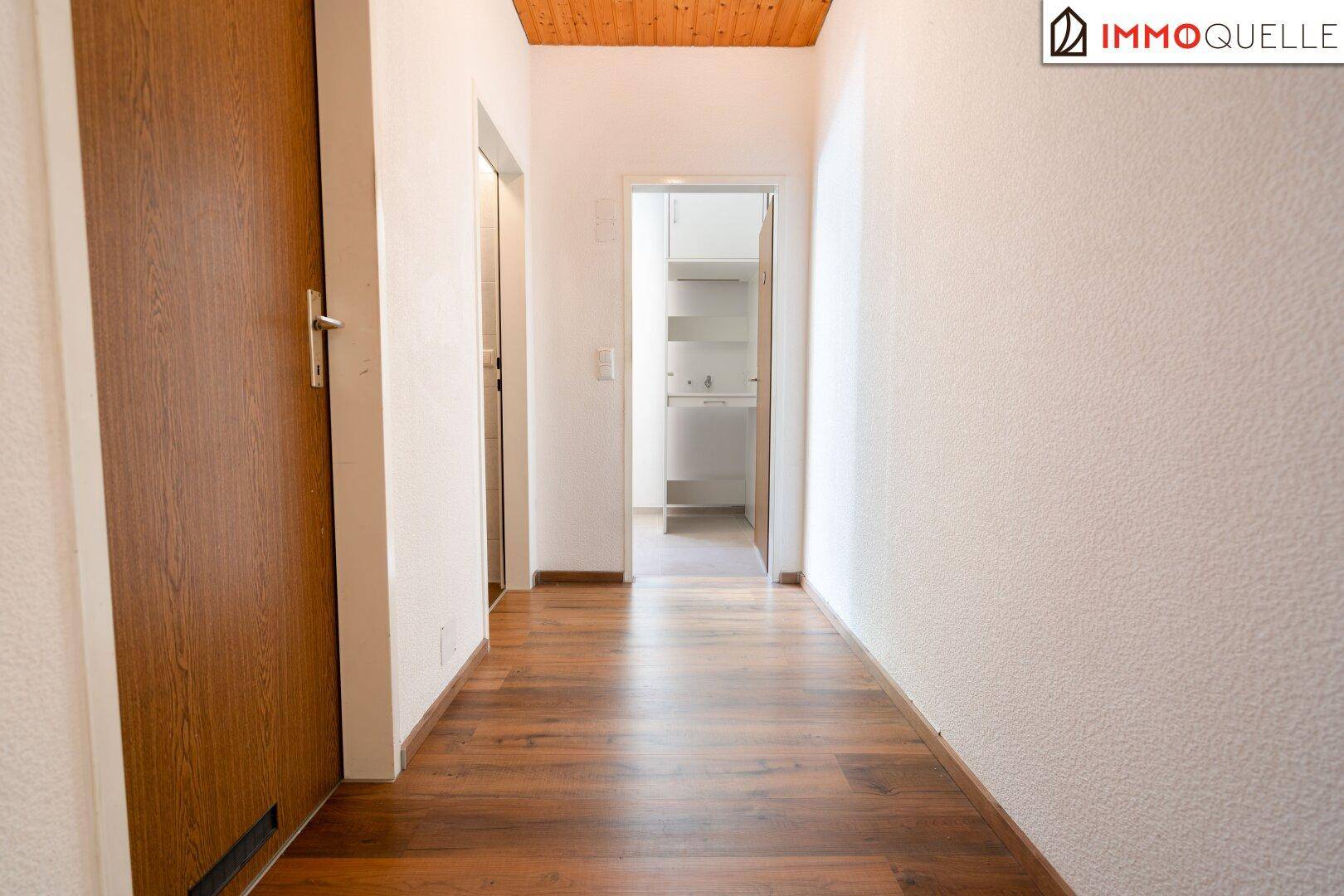 Heller Flur mit Holzboden und Holzdecke, der zu den verschiedenen Räumen führt.