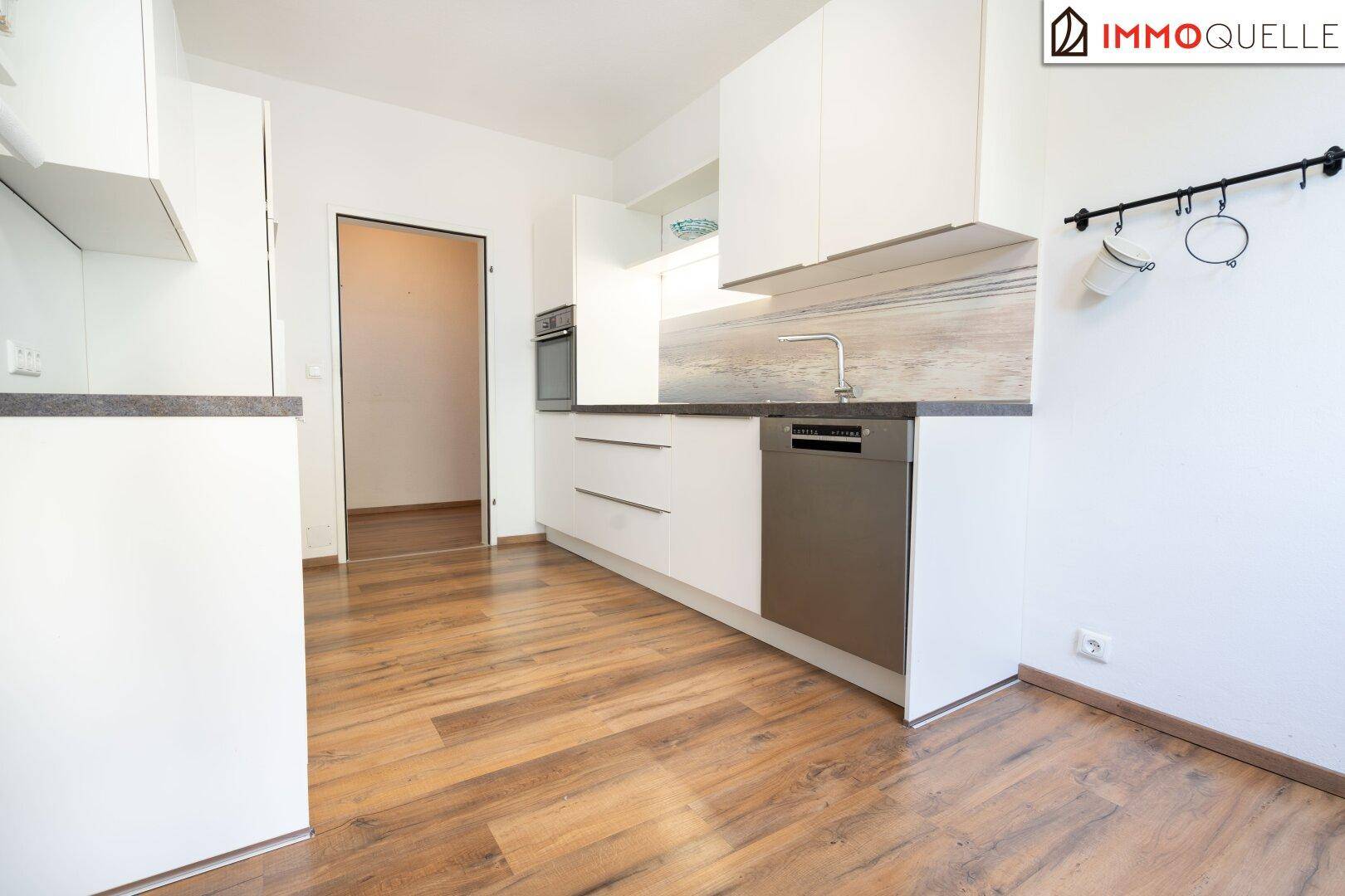 Helle, moderne Küche mit weißen Schränken, Geschirrspüler und Holzboden.
