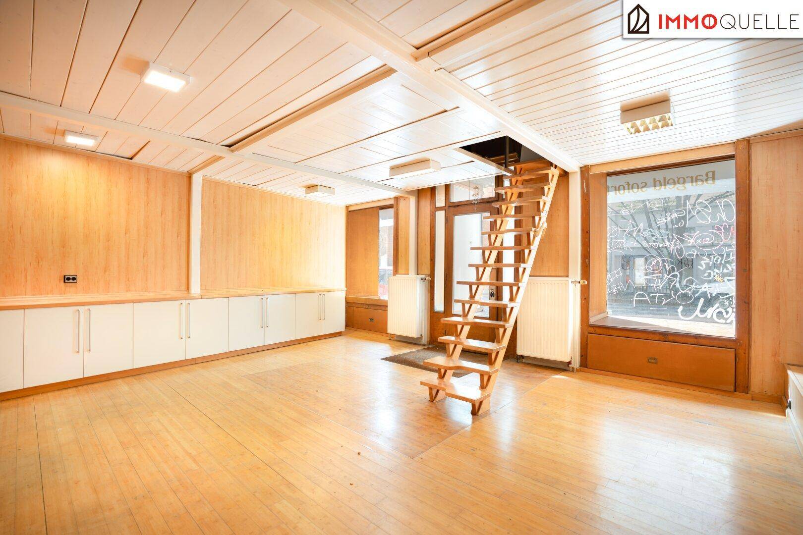 Geräumiger Innenraum mit Holzvertäfelung, Holzboden, Einbauschränken und einer Holztreppe zu einer oberen Ebene.