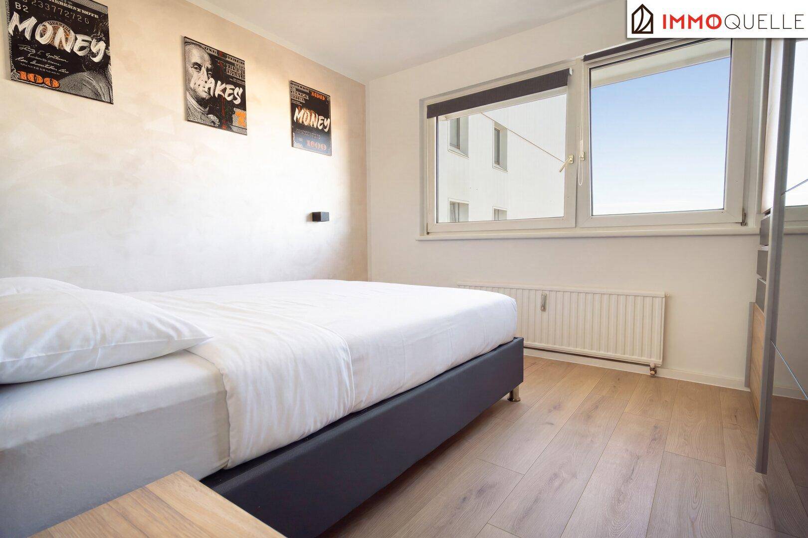 Schlafzimmer mit Doppelbett, Laminatboden und großem Fenster für viel Tageslicht.